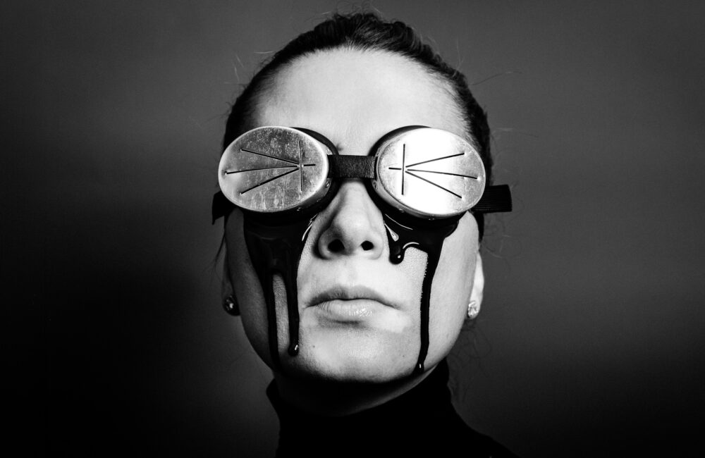 Künstlerische Charakter-Portraits: Nahaufnahme einer Frau mit Brille und flüssigem Latex als schwarze Tränen, fotografiert von einem europaweit tätigen Fotokünstler.