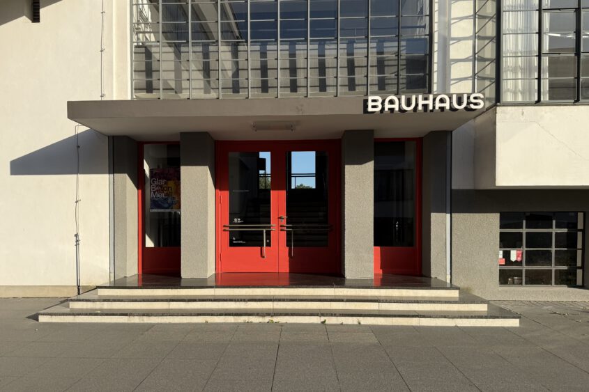 Architekturfotografie in Dessau: Symmetrische Außenansicht des historischen Bauhaus-Gebäudes bei klarem Tageslicht, freies Kunstprojekt von creazyfoto.