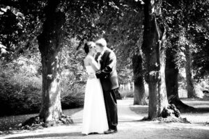 Brautpaar küsst sich unter einer Baumallee im Schlossgarten Glienicke, Schwarzweiß — Hochzeitsfotografie Berlin