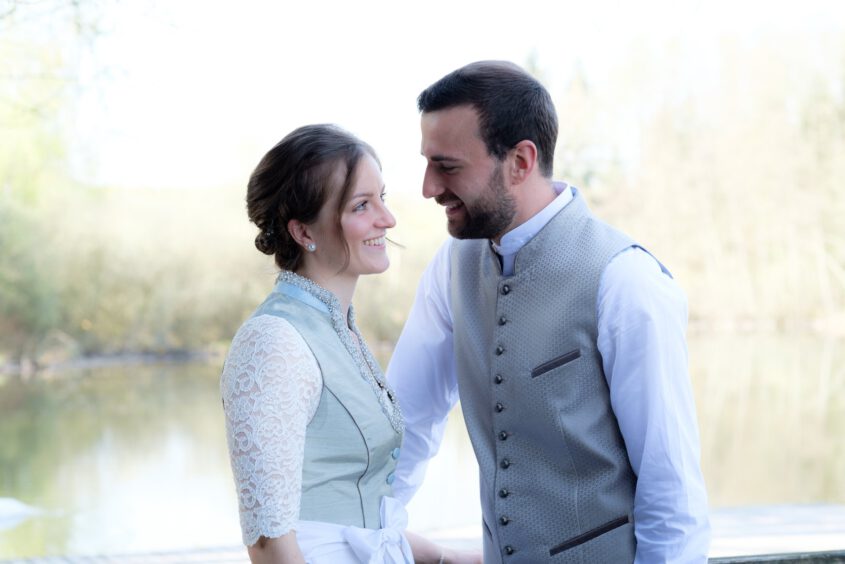 Das Brautpaar lacht am Seeufer des Dießener Weihers – Hochzeit im Allgäu