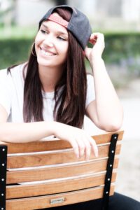 Portrait von Larissa mit Cap auf einer Holzbank – freies Fotoprojekt Stationshoot, Fotograf Heilbronn-Böblingen