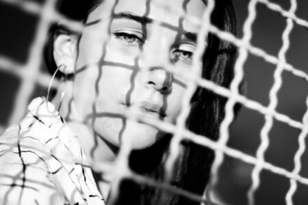 Schwarz-weiß Portrait von Larissa hinter einem Gitter im Treppenhaus – freies Fotoprojekt Stationshoot, Fotograf Heilbronn-Böblingen