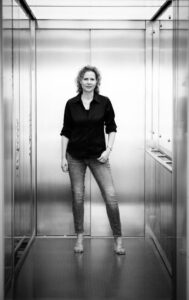 Cineastisches Schwarz-Weiß-Portrait von Coach Annekathrin Straka im Aufzugsbereich on Location in Heilbronn, optimiert für Führungskräfte-Coaching und systemische Beratung Mainz.