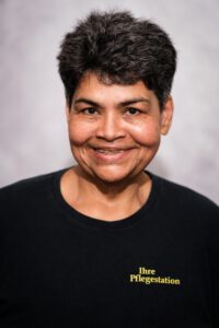 Mitarbeiterin der Pflegestation im Portrait, herzlich lächelnd vor grauem Hintergrund – Portraitfotografie für Pflegedienste, Fotograf Heilbronn