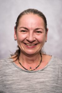 Mitarbeiterin der Pflegestation im Portrait, freundlich lächelnd vor grauem Hintergrund – Portraitfotografie für Pflegedienste, Fotograf Heilbronn