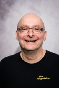 Mitarbeiter der Pflegestation mit Brille im Portrait, lächelnd – Portraitfotografie für Pflegedienste, Fotograf Heilbronn