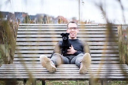 Mann sitzt mit Hund auf einem Holzsteg in der Natur, entspanntes Portrait – Fotograf aus Heilbronn