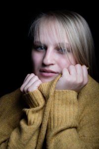 Hier präsentiere ich einige Impressionen aus meinem TFP-Homestudio-Fotoshooting mit Heidi, einer ehemaligen Spielgefährtin meiner Tochter. Es ist erstaunlich, wie die Zeit verfliegt, und die kleinen Kinder von einst plötzlich erwachsen werden, besonders wenn sie irgendwann vor deiner Kamera stehen.
Besonders faszinierend finde ich Portraits mit Pullovern, bei denen das Model mit diesem Element spielt. Auf einem der Bilder zeigt Heidi ihr Gesicht, das leicht von den Haaren verdeckt ist. Sie trägt einen senfgelben, gestrickten Pullover und hält den Kragen mit beiden Händen fest. Der dunkle Hintergrund wurde gewählt, um den Fokus auf die abgebildete Person zu lenken. Es sind diese kleinen Details, die den Charme und die Persönlichkeit eines jeden Portraits ausmachen. 836-Heidi-Portrait-Fotoshooting-copyright-creazyfoto-Fotograf-Heilbronn-Obersulm-Pullover
