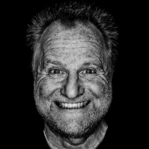 Peter Gödecke lacht, kontrastreiches Schwarzweiß-Selbstporträt vor schwarzem Hintergrund