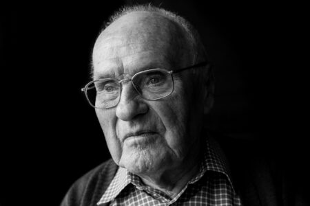 Schwarz-weiß-Portrait eines Seniors mit Brille im Karohemd, ruhiger Blick zur Seite im Fensterlicht – Projekt Lebensspuren, Fotograf Heilbronn-Allgäu-Hamburg-Bremen