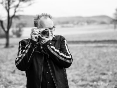 Peter Gödecke fotografiert vor Feld und Hügeln im Raum Heilbronn, Porträt von Andrea Kopp