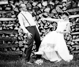 Brautpaar posiert ausgelassen vor einem Brennholzstapel, Hochzeit im Raum Heilbronn, schwarzweiß