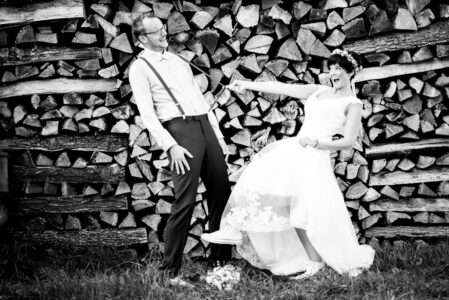 Brautpaar posiert ausgelassen vor einem Brennholzstapel, Hochzeit im Raum Heilbronn, schwarzweiß