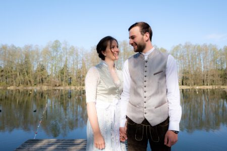Brautpaar am Ufer des Dießener Weihers, kahle Bäume im April – Hochzeitsfotograf Allgäu