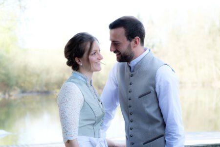 Das Brautpaar lacht am Seeufer des Dießener Weihers – Hochzeit im Allgäu