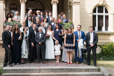 Die Hochzeitsgesellschaft auf der Freitreppe des Standesamts Zehlendorf, Blütenblätter auf den Stufen.