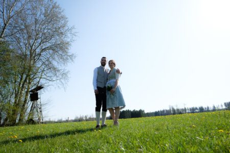 Brautpaar auf einer Wiese über Waal, weiter Himmel – Hochzeit im Allgäu