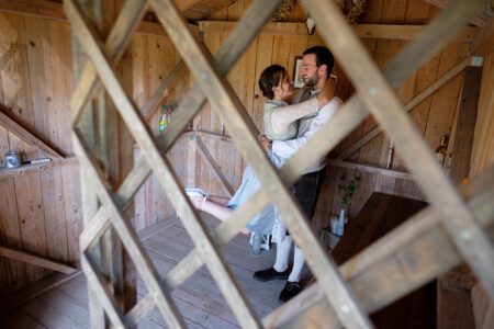 Blick durch ein Holzgitter auf das Brautpaar in der Scheune – Hochzeitsfotograf Allgäu