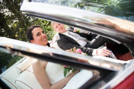 Sarah und Timo im offenen Cabrio, gesehen durch die Windschutzscheibe.