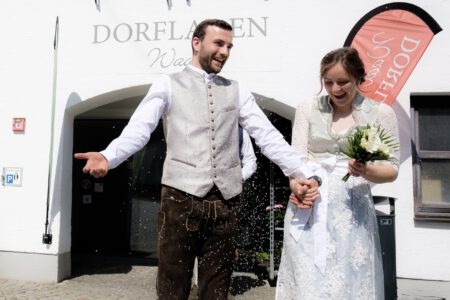 Reis fliegt: das Brautpaar vor dem Dorfladen in Waal – Hochzeitsfotograf Allgäu